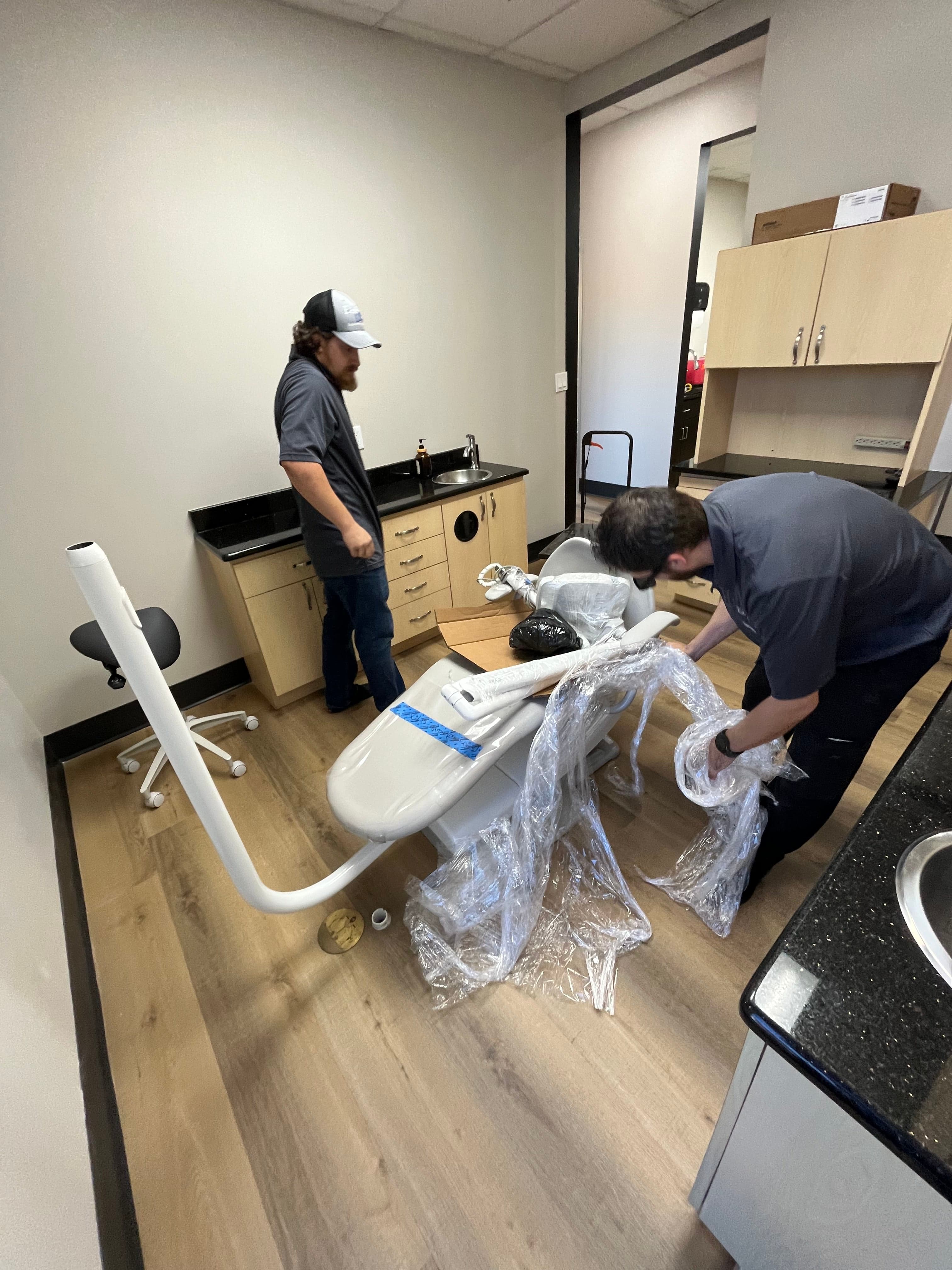 Technicians unwrapping used dental chair for installation in Texas operatory